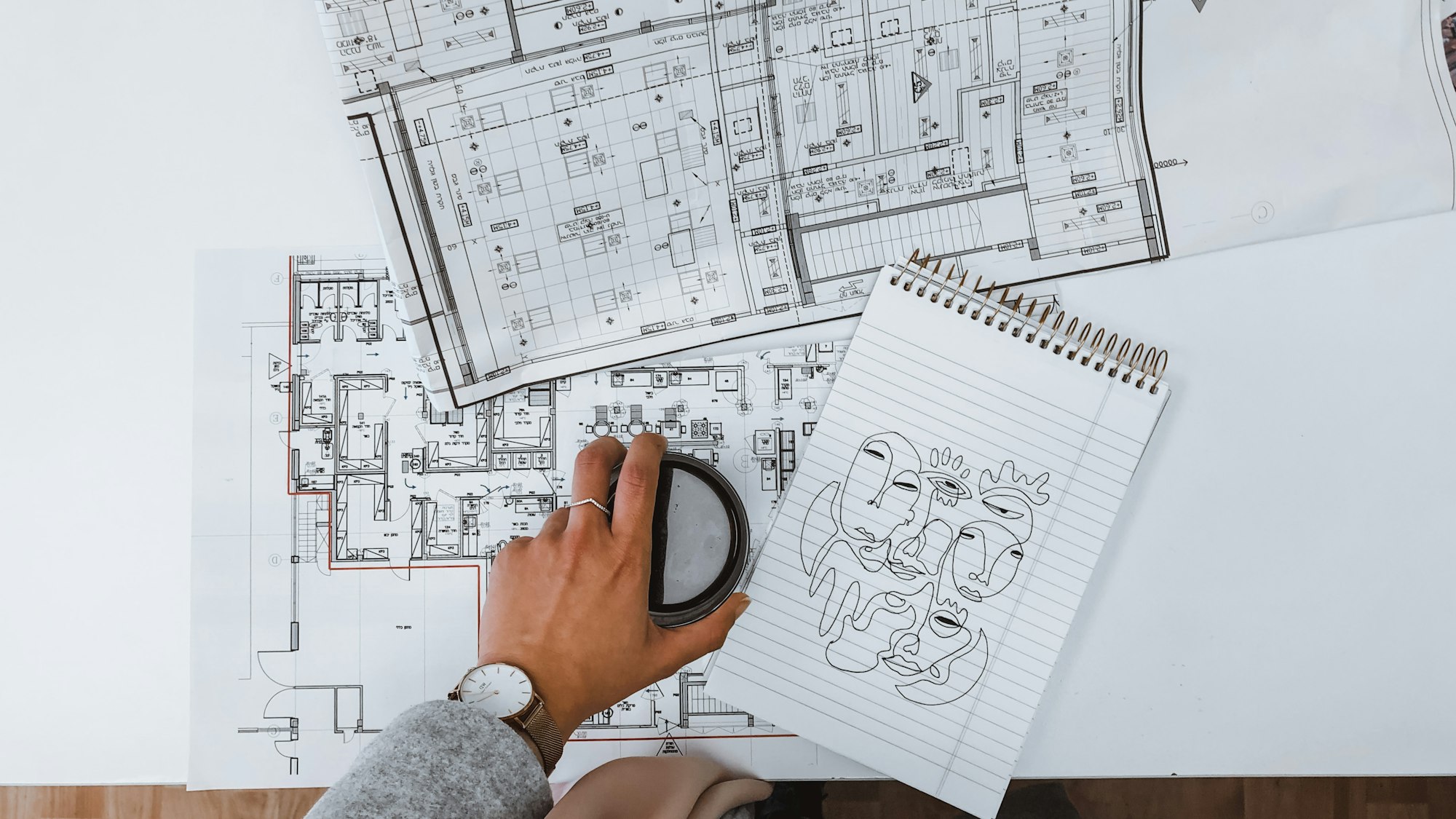 Hands interrogating construction drawings with a scale rule